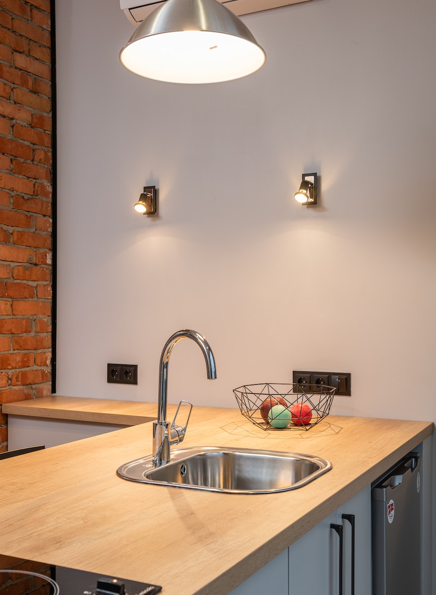 Interior of contemporary apartment with kitchen counter with built in sink and pendant lamp