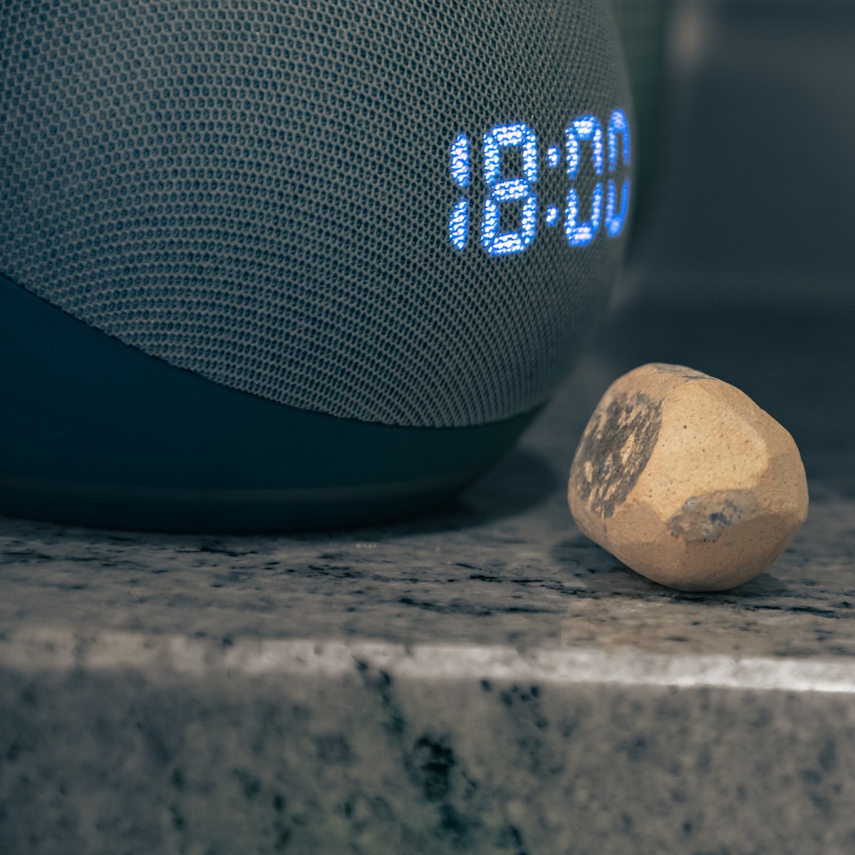a bluetooth speaker sitting next to a rock